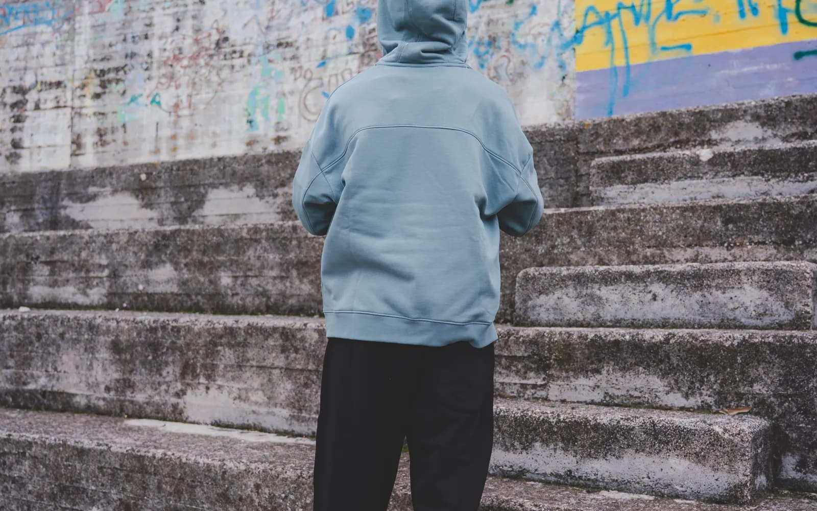 Capo streetwear Sister Sport fotografato di spalle davanti a un muro di graffiti
