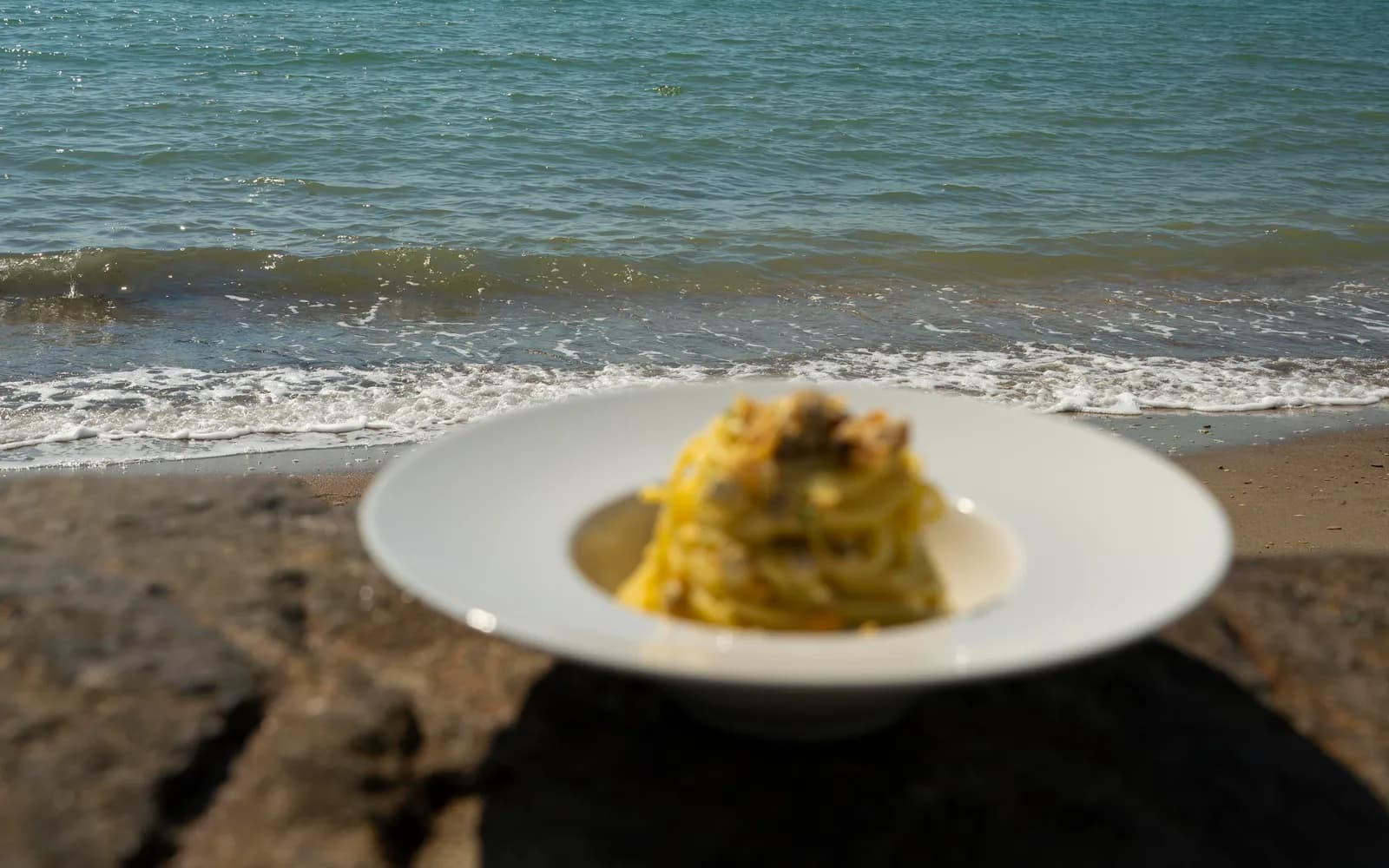 Piatto servito sulla battigia con il mare di Ostia sullo sfondo