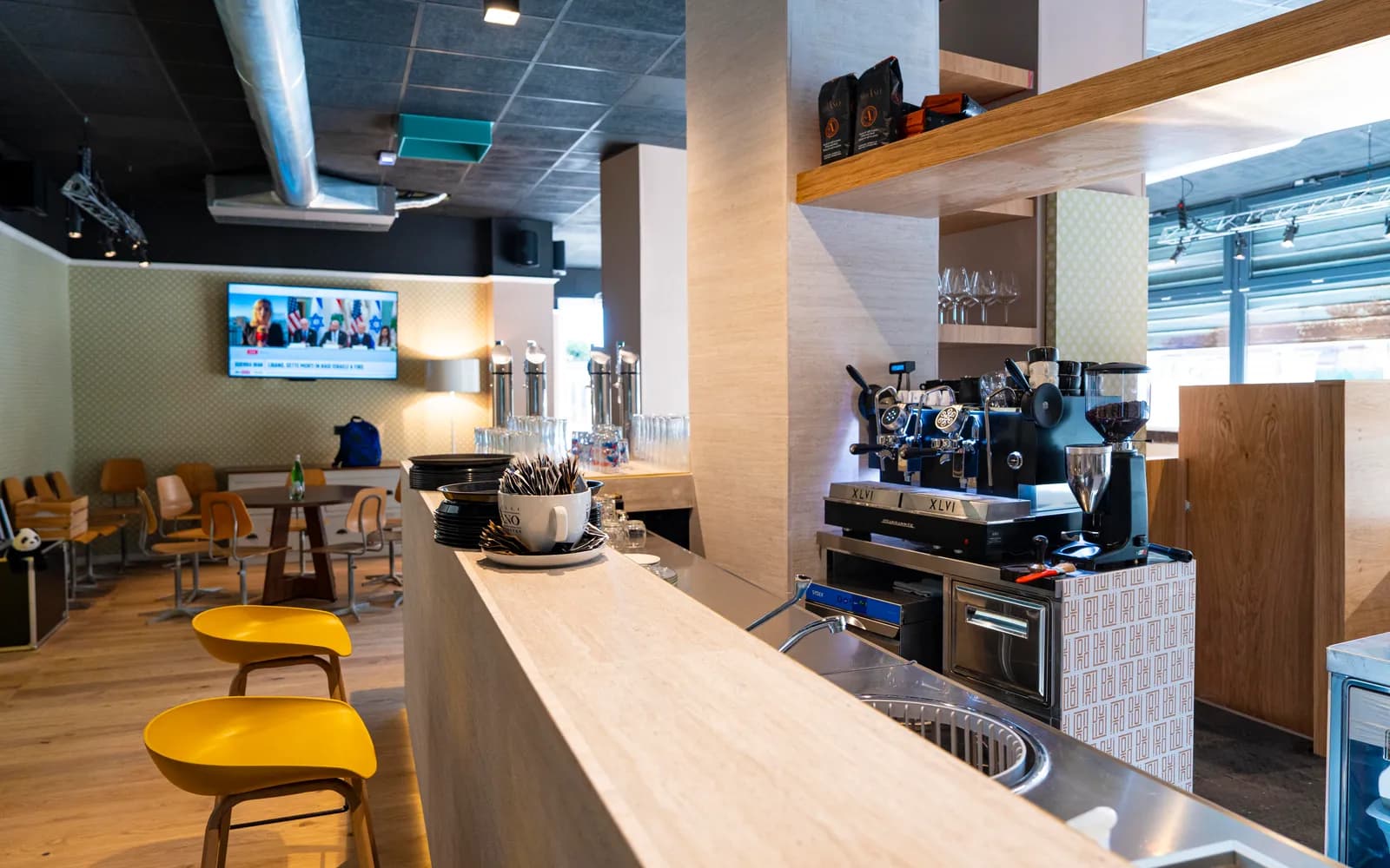 Il bancone bar di Duilio con la macchina del caffè e le sedute gialle