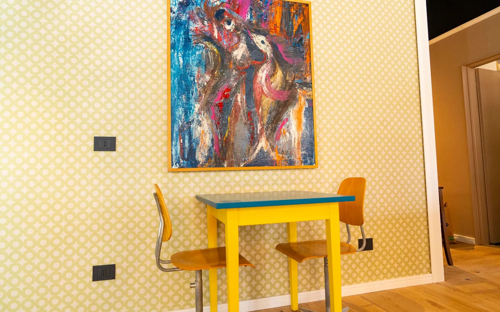 Interni di Duilio: opera d'arte alla parete e tavolo giallo e blu