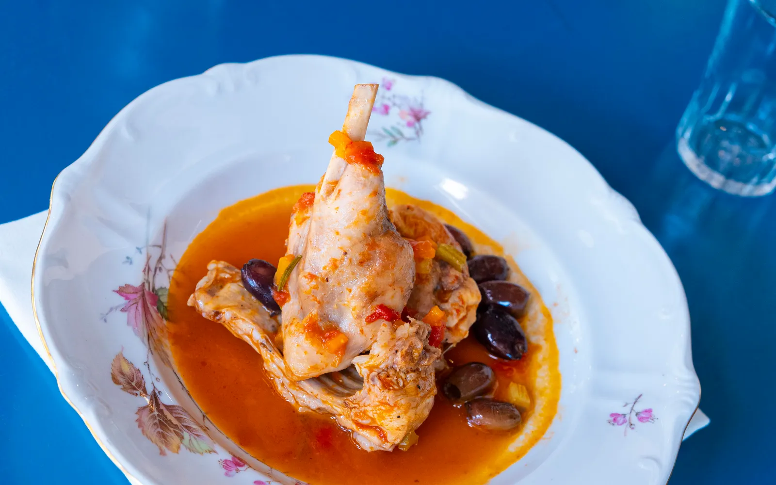 Piatto di pollo in umido con olive servito su porcellana decorata