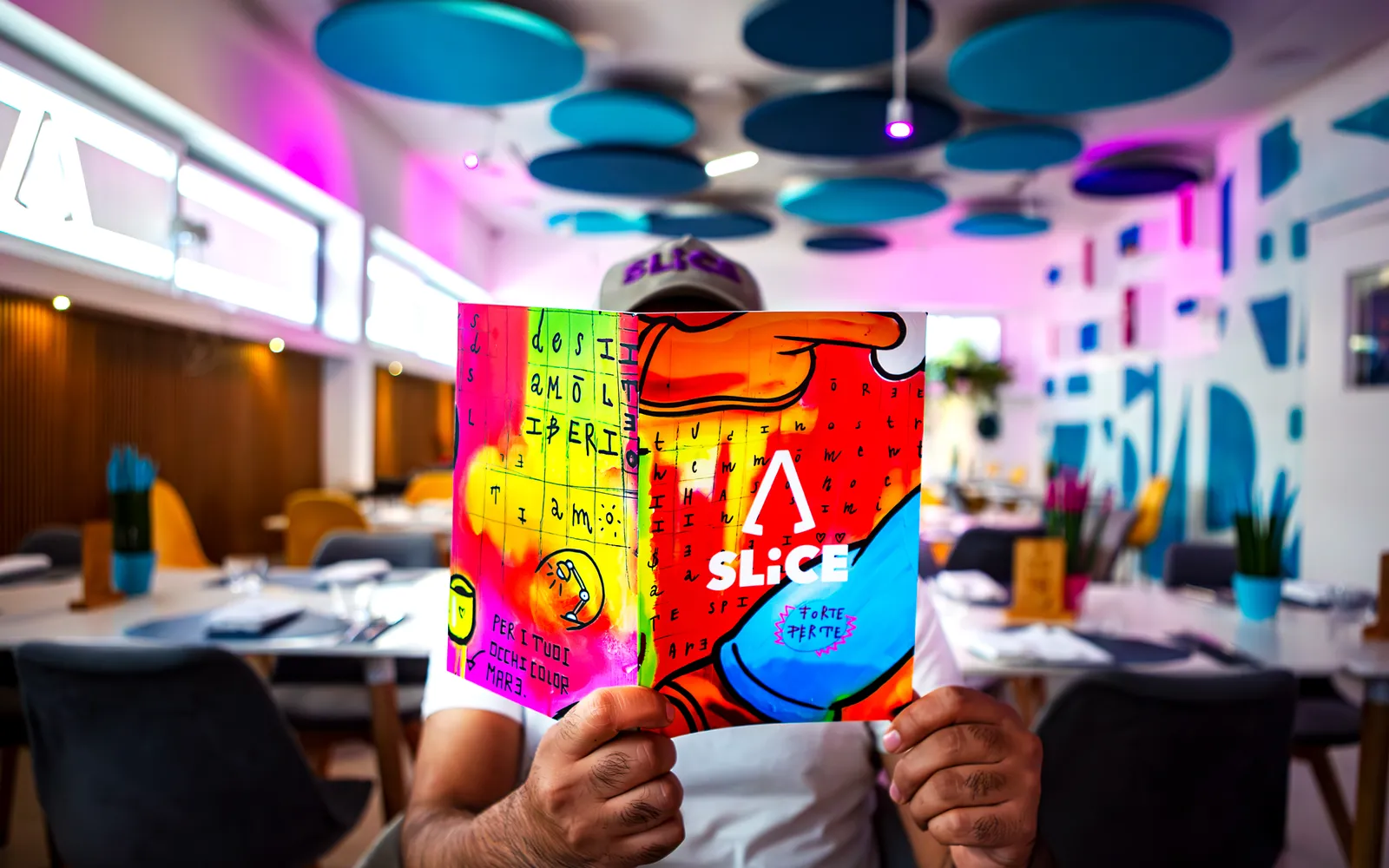 Gli interni di Slice of Capanno, con il menù illustrato e le luci colorate